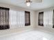 Bright bedroom features white tile flooring, a ceiling fan and well-lit windows with decorative curtains at 13003 Sandburst Ln, Hudson, FL 34667