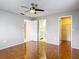 Bedroom with a ceiling fan, wood-look flooring, and ensuite bathroom and closet access at 13003 Sandburst Ln, Hudson, FL 34667