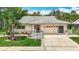 Charming single-story home featuring a well-manicured lawn, lush landscaping, and an attached two-car garage at 13003 Sandburst Ln, Hudson, FL 34667