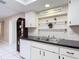 Charming kitchen featuring black countertops, white cabinets, and decorative shelving at 13003 Sandburst Ln, Hudson, FL 34667