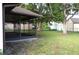 Backyard view featuring the home, screened in porch, lush green grass, and large shade trees at 13425 Bonita Ave, Spring Hill, FL 34609