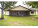 Backyard view featuring the home, screened in porch, and large shade trees at 13425 Bonita Ave, Spring Hill, FL 34609