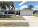 Exterior front view of the home with a two car garage and neutral paint with stone accents at 1402 Tallahassee Dr, Tarpon Springs, FL 34689