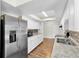 Bright kitchen featuring stainless steel fridge, tile backsplash, speckled countertops, and wood-look flooring at 1402 Tallahassee Dr, Tarpon Springs, FL 34689