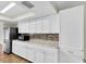 Bright kitchen featuring white cabinets, stainless steel fridge, mosaic backsplash, and speckled countertops at 1402 Tallahassee Dr, Tarpon Springs, FL 34689