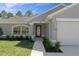 Charming front entrance featuring a decorative front door with sidelights, manicured bushes, and a well-kept lawn at 15291 Green Jay Rd, Weeki Wachee, FL 34614