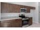 Modern kitchen featuring stainless appliances, stone countertops, and dark wood cabinets with stylish knobs at 15291 Green Jay Rd, Weeki Wachee, FL 34614