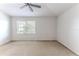 Bright carpeted bedroom with a large window, neutral walls, and a ceiling fan, creating a serene and inviting space at 15846 Stable Run Dr, Spring Hill, FL 34610