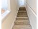 Carpeted staircase leading to the upper level of the home features white risers and stringers and a white handrail at 15846 Stable Run Dr, Spring Hill, FL 34610