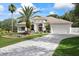 Elegant exterior with lush landscaping, palm trees, water feature, and a paver driveway to a two-car garage at 18644 Autumn Lake Blvd, Hudson, FL 34667