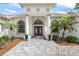 Elegant entryway featuring double doors, columns, manicured landscaping, and a patterned paver walkway at 18644 Autumn Lake Blvd, Hudson, FL 34667