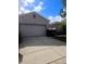 Beige home showcasing a two-car garage, complimented by lush landscaping and concrete driveway under a partly cloudy sky at 20720 Eustis Rd, Land O Lakes, FL 34637