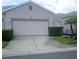 Beige home showcasing a two-car garage, complimented by lush landscaping and concrete driveway at 20720 Eustis Rd, Land O Lakes, FL 34637