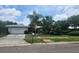 Charming home featuring a two-car garage, palm trees, and well-manicured landscaping at 2083 Envoy Ct, Clearwater, FL 33764