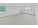 A sunlit and empty living room features neutral carpet, bright windows and a white front door at 2402 Ecuadorian Way # 40, Clearwater, FL 33763