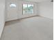 An empty sunlit living room with neutral carpet, a bright window and white front door at 2402 Ecuadorian Way # 40, Clearwater, FL 33763