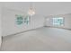 An empty sunlit living room featuring neutral carpet, bright windows and white walls at 2402 Ecuadorian Way # 40, Clearwater, FL 33763