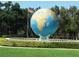 Unique blue and gold globe statue with surrounding greenery and the American flag at 2402 Ecuadorian Way # 40, Clearwater, FL 33763