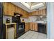 Functional kitchen includes black appliances, white tile floors, and wooden cabinetry at 306 Martha Ln # 42, Oldsmar, FL 34677