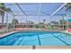 Screened-in pool provides a refreshing escape with vibrant floral accents and clear blue skies at 3352 Gulfview Dr, Hernando Beach, FL 34607