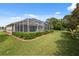 Expansive backyard featuring a screened-in pool enclosure and lush greenery, perfect for outdoor relaxation at 3400 Rosebay Ct, Spring Hill, FL 34609