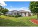 Beautiful backyard featuring a screened-in pool, lush lawn, and manicured landscaping and garden beds at 3400 Rosebay Ct, Spring Hill, FL 34609