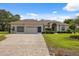Charming single-story home featuring a well-manicured lawn, brick driveway, and three-car garage at 3400 Rosebay Ct, Spring Hill, FL 34609