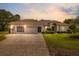 Charming single-story home featuring a well-manicured lawn, brick driveway, and three-car garage at 3400 Rosebay Ct, Spring Hill, FL 34609