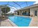 Gorgeous screened-in pool with a rock waterfall feature, surrounded by a spacious patio and lush landscaping at 3400 Rosebay Ct, Spring Hill, FL 34609