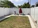 Backyard with white fence, patio, Adirondack chairs, umbrella, and lush green grass at 406 Driftwood E Dr, Palm Harbor, FL 34683