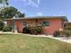 View of the exterior side of the home with lush landscaping, well-kept lawn and bougainvillea at 406 Driftwood E Dr, Palm Harbor, FL 34683