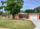 Charming single-story home with an attached garage, lush green lawn, and mature trees in a desirable neighborhood at 406 Driftwood E Dr, Palm Harbor, FL 34683