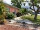 Close-up view of the home's side yard featuring creative landscaping with mulch, rocks, and various shrubbery at 406 Driftwood E Dr, Palm Harbor, FL 34683