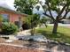 The side yard has trees, rocks, grass, and a clear view of the street at 406 Driftwood E Dr, Palm Harbor, FL 34683