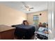 Comfortable bedroom features a ceiling fan and dark bedding along with a desk area for working at home at 4148 Landover Blvd, Spring Hill, FL 34609