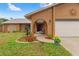 Charming home exterior with manicured flower beds, arched entryway, and attached two-car garage at 4190 Lema Dr, Spring Hill, FL 34609