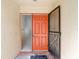 Close-up of a vibrant orange front door with adjacent glass panel and decorative screen door at 4420 Marine Pkwy, New Port Richey, FL 34652