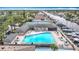 Aerial view of a community pool with lounge chairs and tables, a tennis court, and boats docked along the canal at 4420 Marine Pkwy, New Port Richey, FL 34652