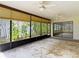 A sunroom with dual ceiling fans and views of the surrounding trees and neighborhood through screened windows at 4420 Marine Pkwy, New Port Richey, FL 34652