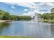 Scenic view of community pond with fountain, dock and gazebo, framed by lush trees and a bright, cloudy sky at 4837 Boonesboro Ct, New Port Richey, FL 34655