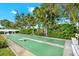 Outdoor shuffleboard court with green surface and benches, surrounded by lush landscaping and mature trees at 4939 Floramar Ter # 204, New Port Richey, FL 34652
