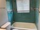 Bathroom featuring unique blue tile, a tub, and a window at 5023 Queen Palm Dr, New Port Richey, FL 34652