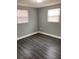 Bedroom featuring grey walls, two windows, and dark wood-look vinyl floors at 5023 Queen Palm Dr, New Port Richey, FL 34652
