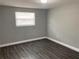 Simple bedroom features a window, light gray walls and matching gray floors at 5023 Queen Palm Dr, New Port Richey, FL 34652