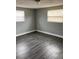 Bedroom with two windows, grey walls, and dark wood-look vinyl floors at 5023 Queen Palm Dr, New Port Richey, FL 34652