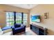 Cozy living area with a view of the front yard, a comfortable blue chair, and a modern entertainment center at 5152 Panther Dr, Spring Hill, FL 34607