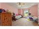 Bright bedroom with pink walls, plush carpeting, and a large window, creating a warm and inviting atmosphere at 5216 Hope Ln, Spring Hill, FL 34606