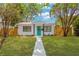 Charming single-story home with lush green lawn, modern teal door and mature trees at 5753 2Nd N Ave, St Petersburg, FL 33710