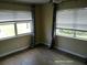 A bedroom with hardwood floors, two windows, a ceiling fan, and gray curtains at 7419 E Comanche Ave, Tampa, FL 33610