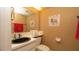 Bathroom with sink, toilet, and decorative elements; red towels add color at 7501 Woodbox Row, Hudson, FL 34667